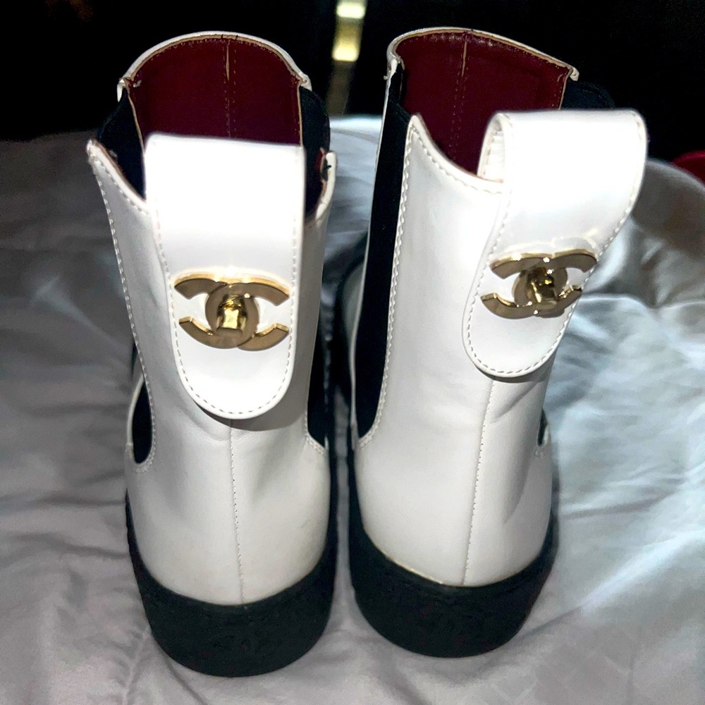 Womens black and white Chanel boots with red interior and gold CC symbol on Back